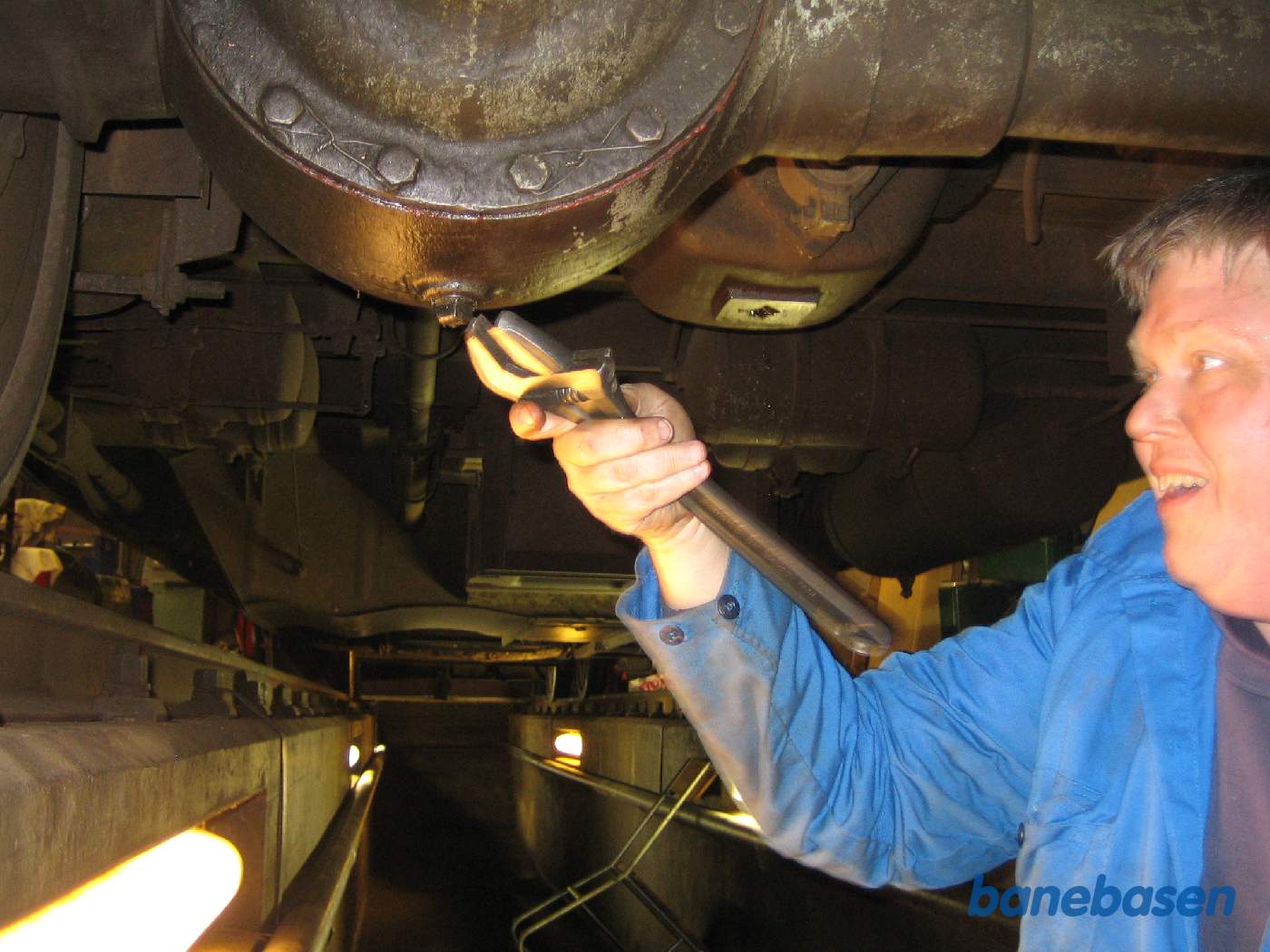 Olieskift på den bagerste aksel på motorbogien. Hjulakslen over hovedet på personen og den trækkende aksel over hovedet på fotografen
