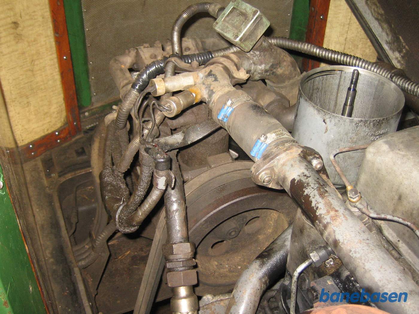 Foran motoren sidder trykluftpumpen der drives gennem kileremmene. Til højre ses centrifugaloliefilteret, den åbne dåse med pinden i midten