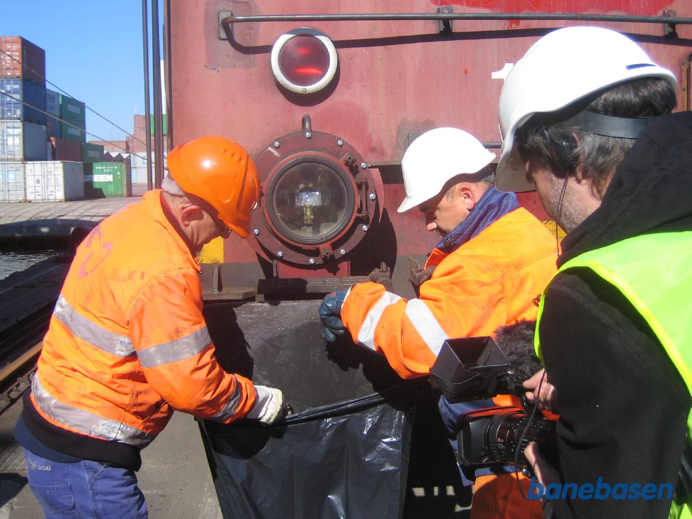 Olie og fedt skrabes af pufferne og ned i den sorte plastsæk mens en fotograf filmer det hele