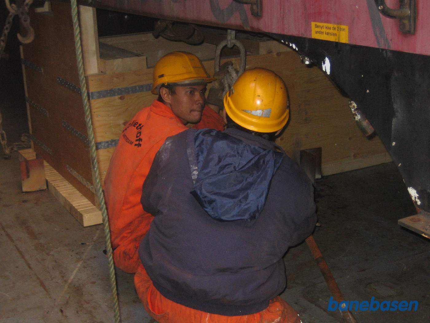 Her er 2 mand ved at fastgøre kæderne til vognkassen