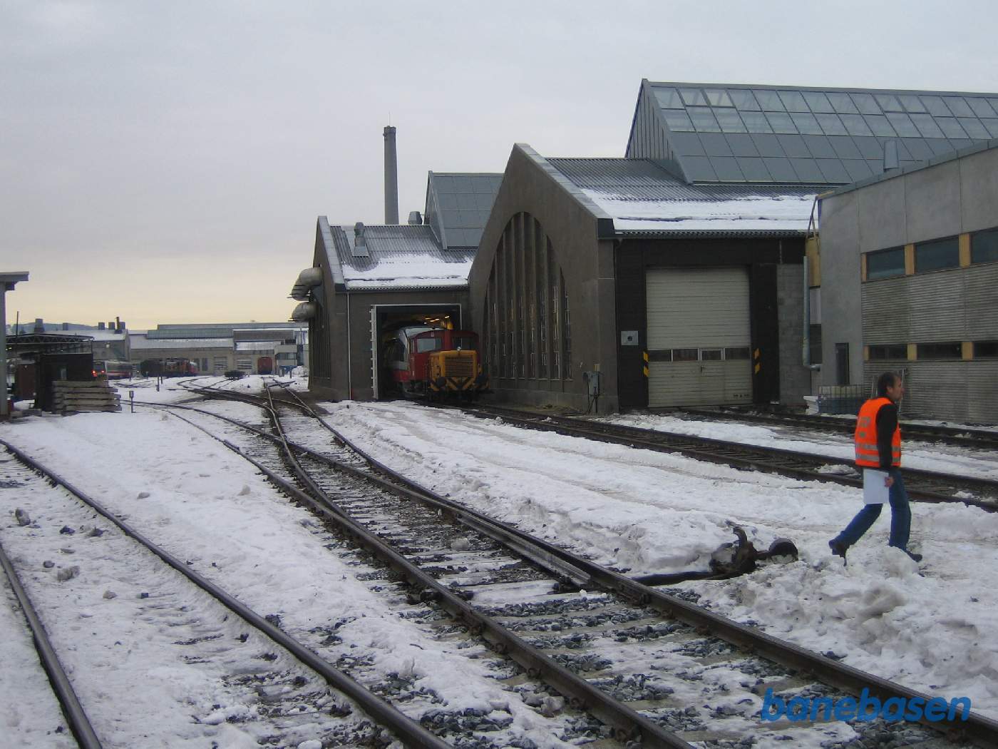 En DSB mand krydser over de sneklædte spor udenfor værkstedet