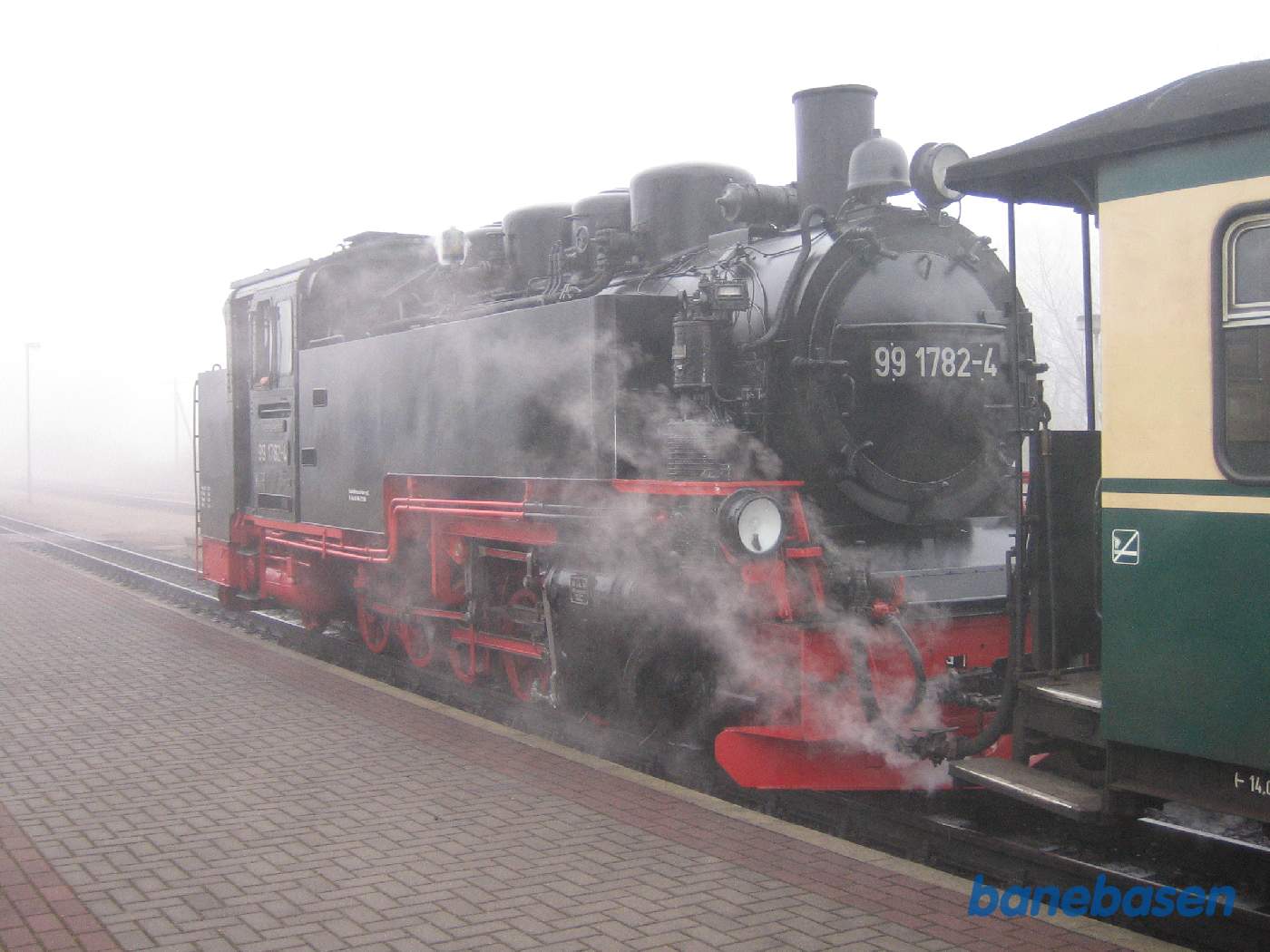 Et damplokomotiv i røg og damp ved perron