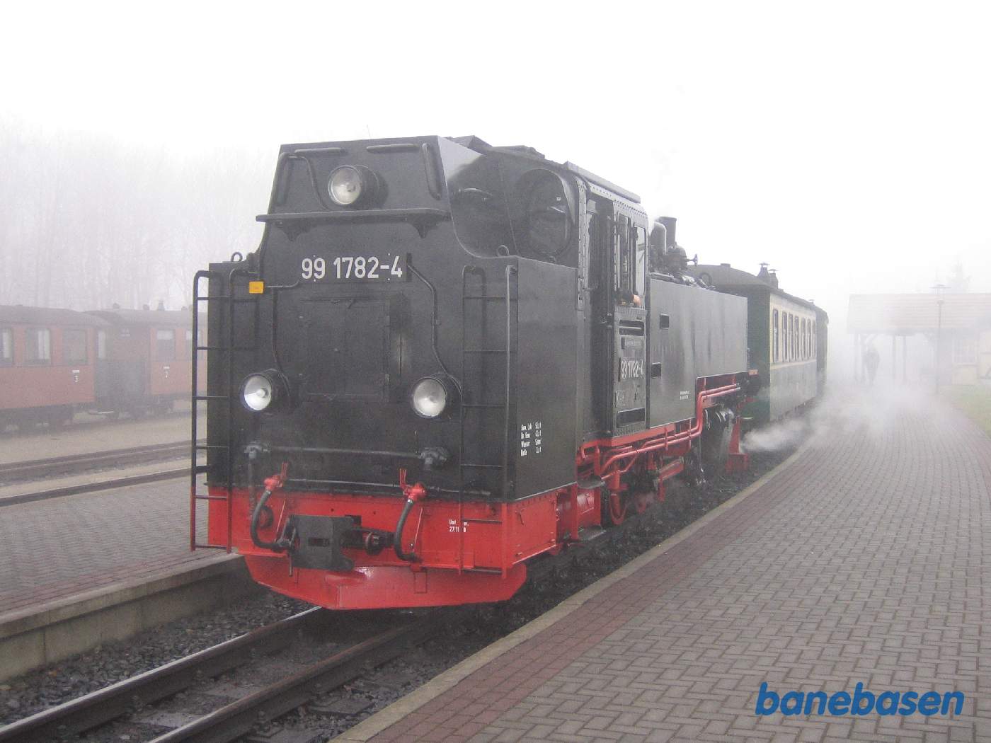 Et damplokomotiv i røg og damp ved perron