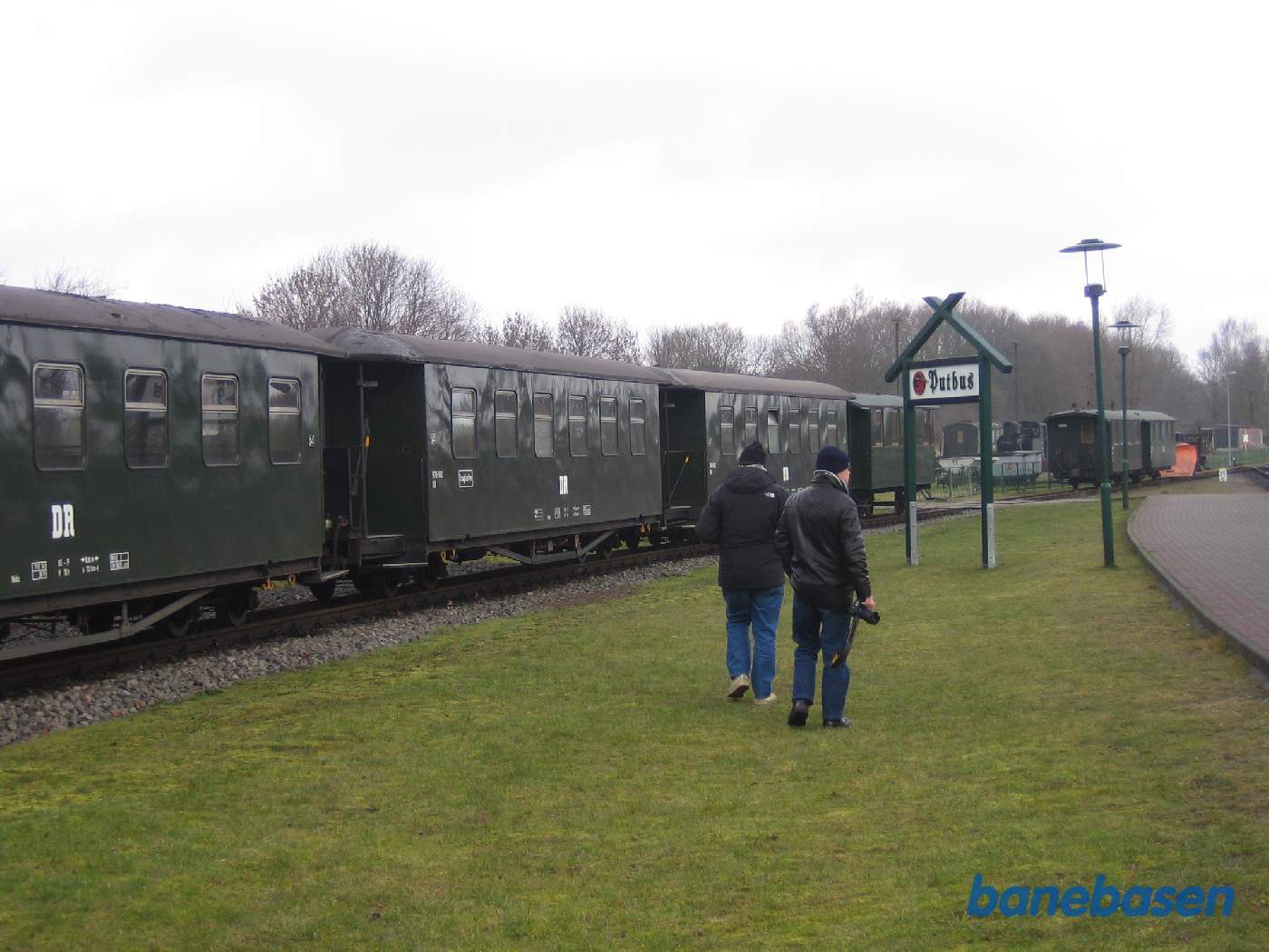 2 turister går på græsplænen og kigger på vogne
