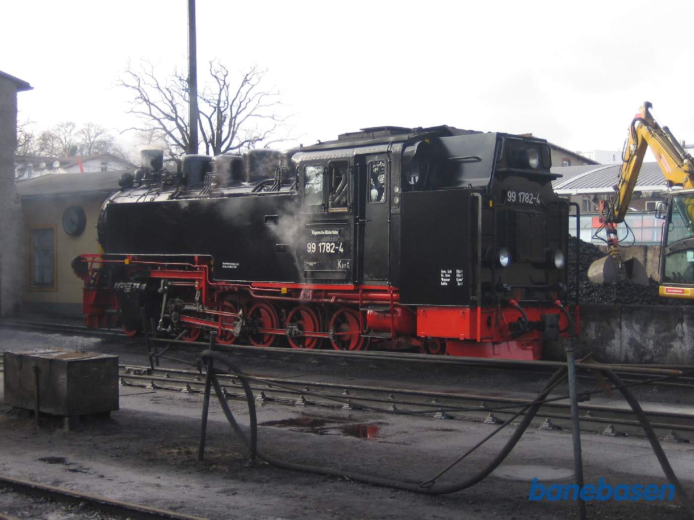 Et varmt damplokomotiv foran remisen