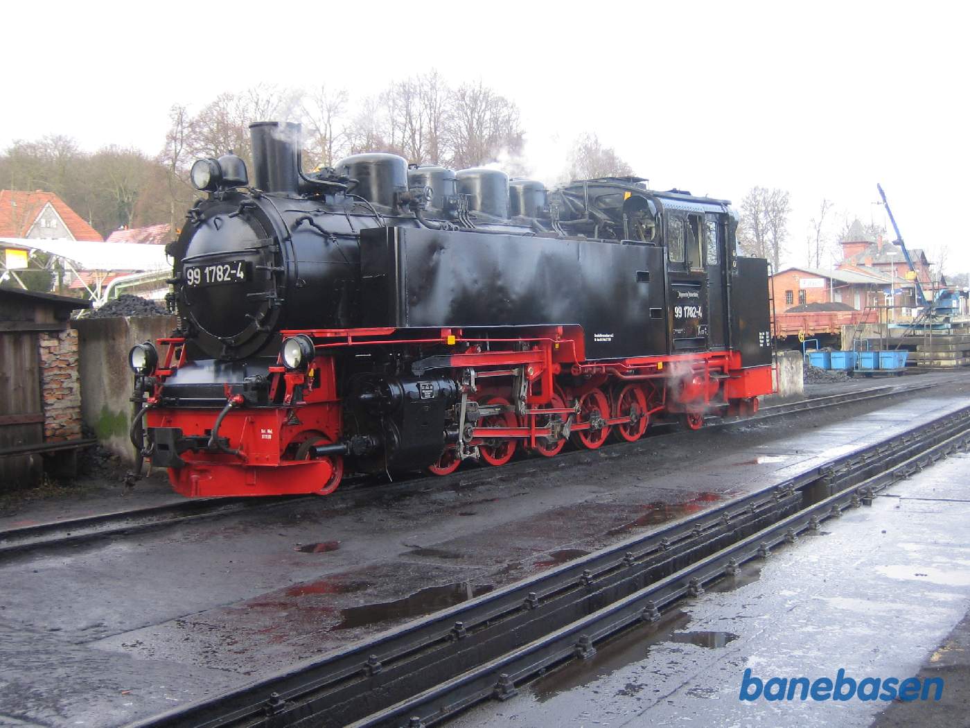 Et varmt damplokomotiv foran remisen