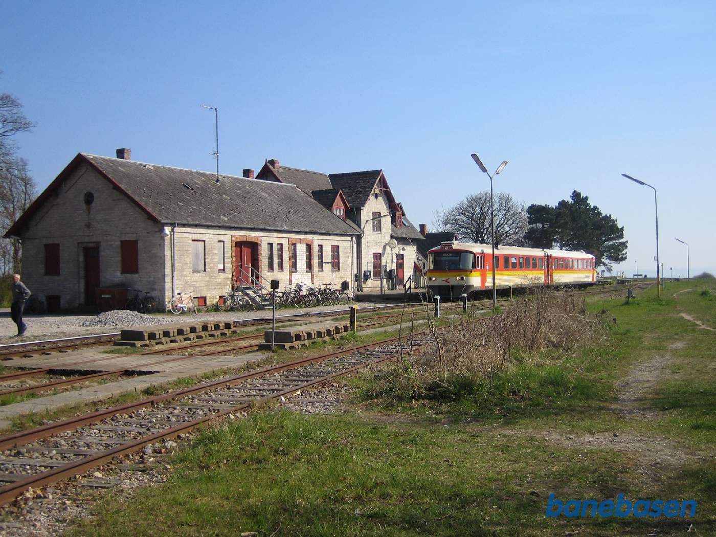 Persontoget holder ved perron, varehus og stationsbygning til venstre. Havet ses ude til højre for enden af banen
