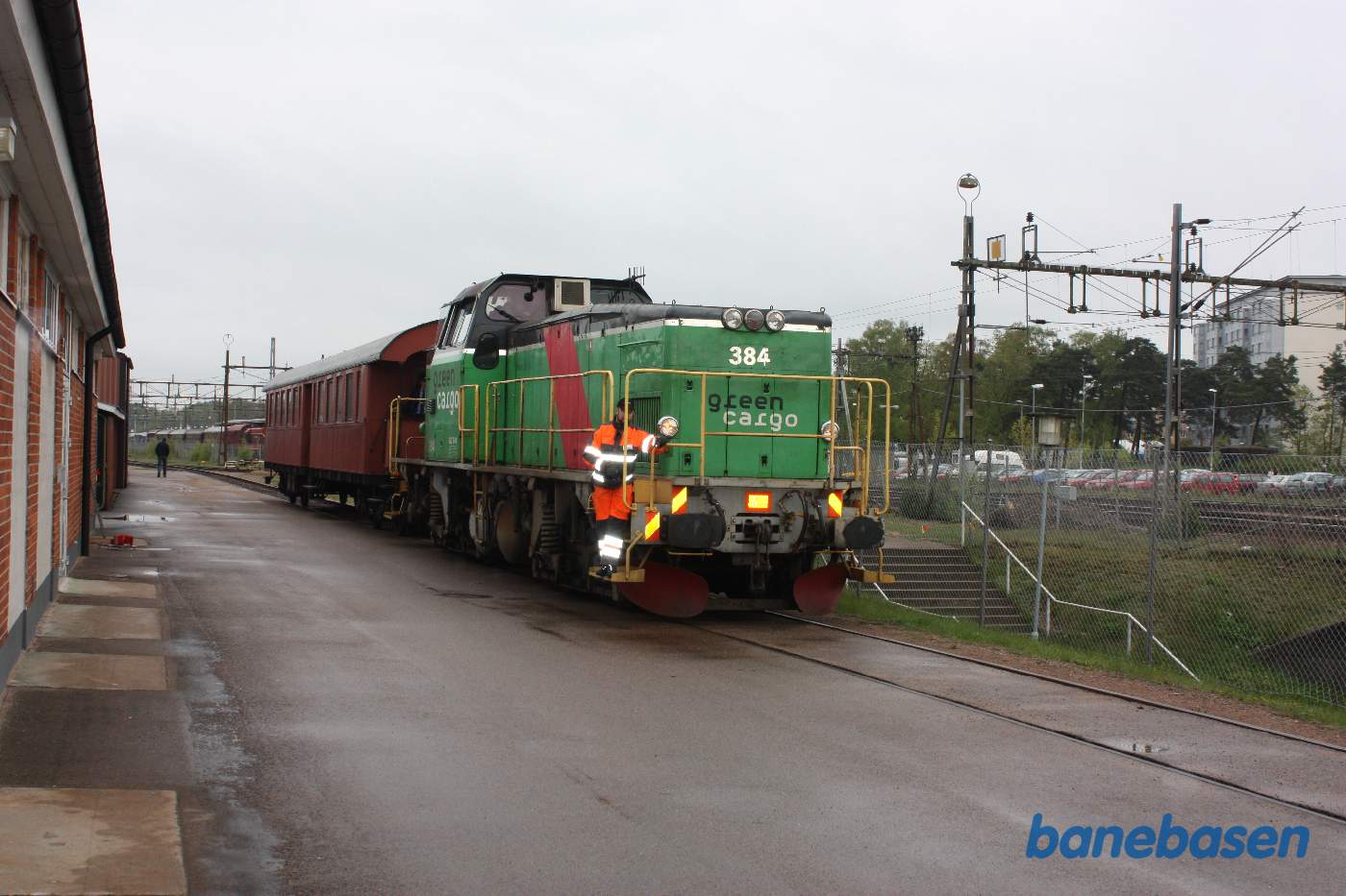 Et grønt lokomotiv med en personvogn passerer museet