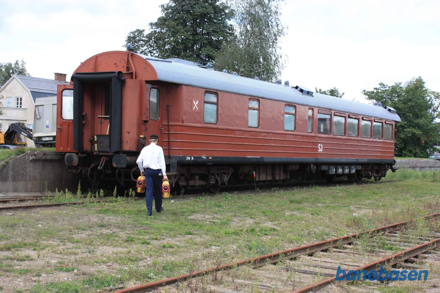 En spisevogn i sidesporet. Togbetjenten går med 2 slutlamper