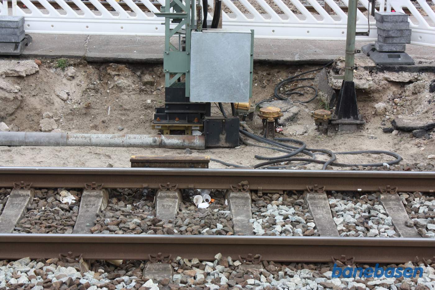 En INDUSI signalmagnet styret af et armsignal. Wiretrækket til signalet ligger i røret og man kan se wiren gå op i metalkassen