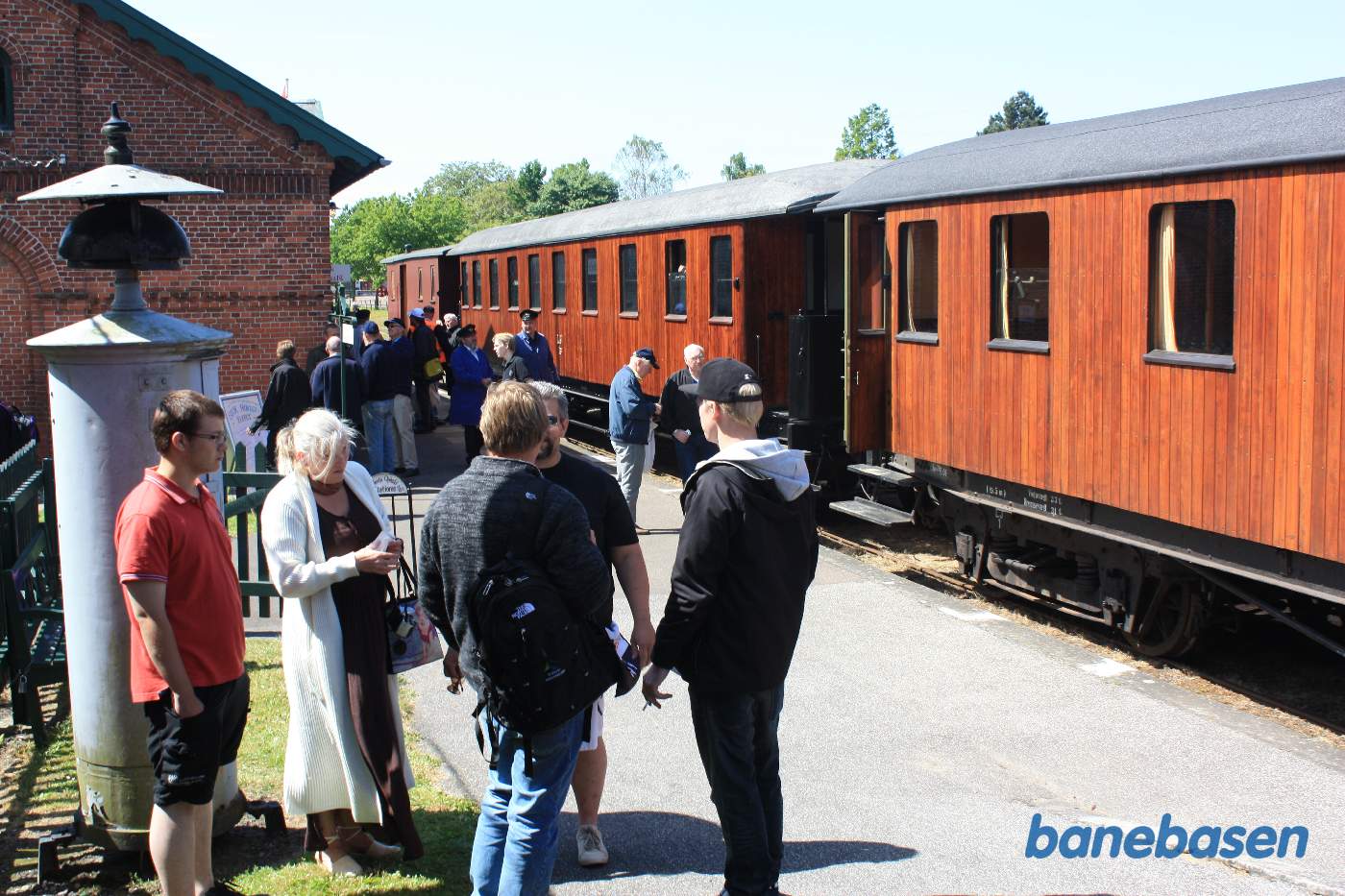 Persontoget holder ved perron, stationsbygningen inde til venstre