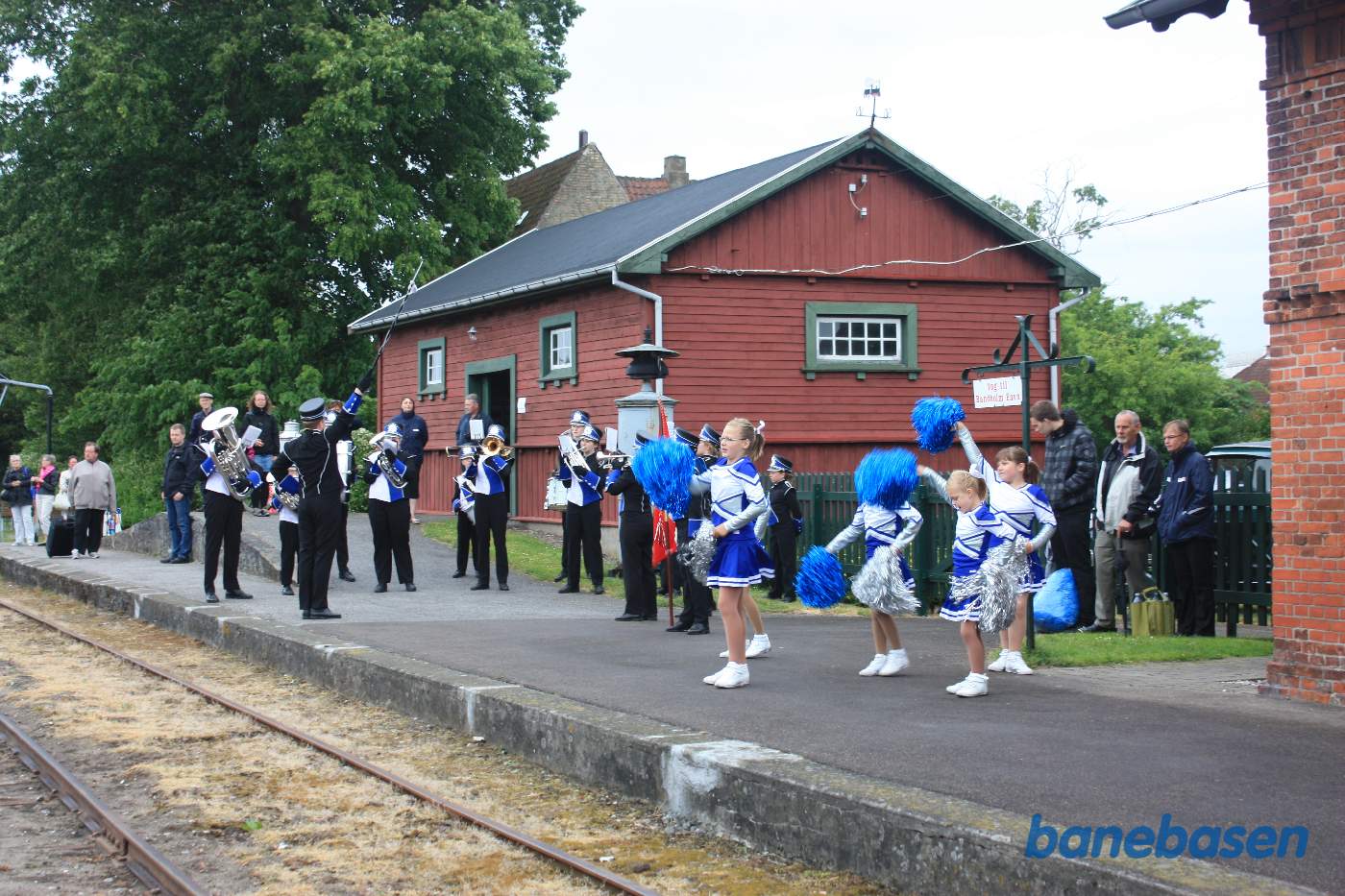 Musikkorpset spiller musik på perronen mens pigerne danser til Musikkorpset spiller musik på perronen mens pigerne danser til