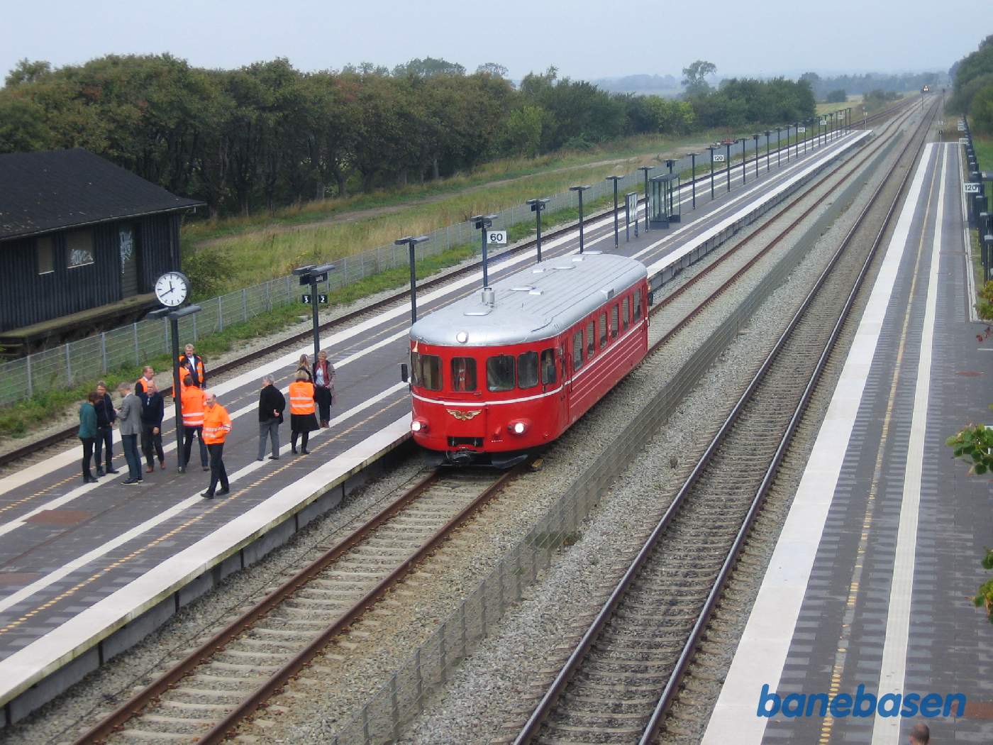 Skinnebussen afventer overhaling, set oppe fra den nye gangbro. Det overhalende tog ses ude i horisonten