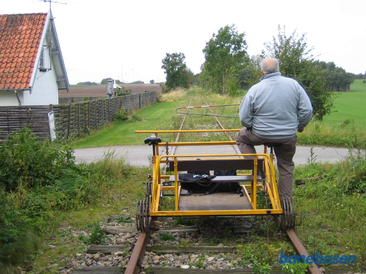 Cyklisten holder foran Lerbjergvej. Stationsbygningen ses inde til venstre