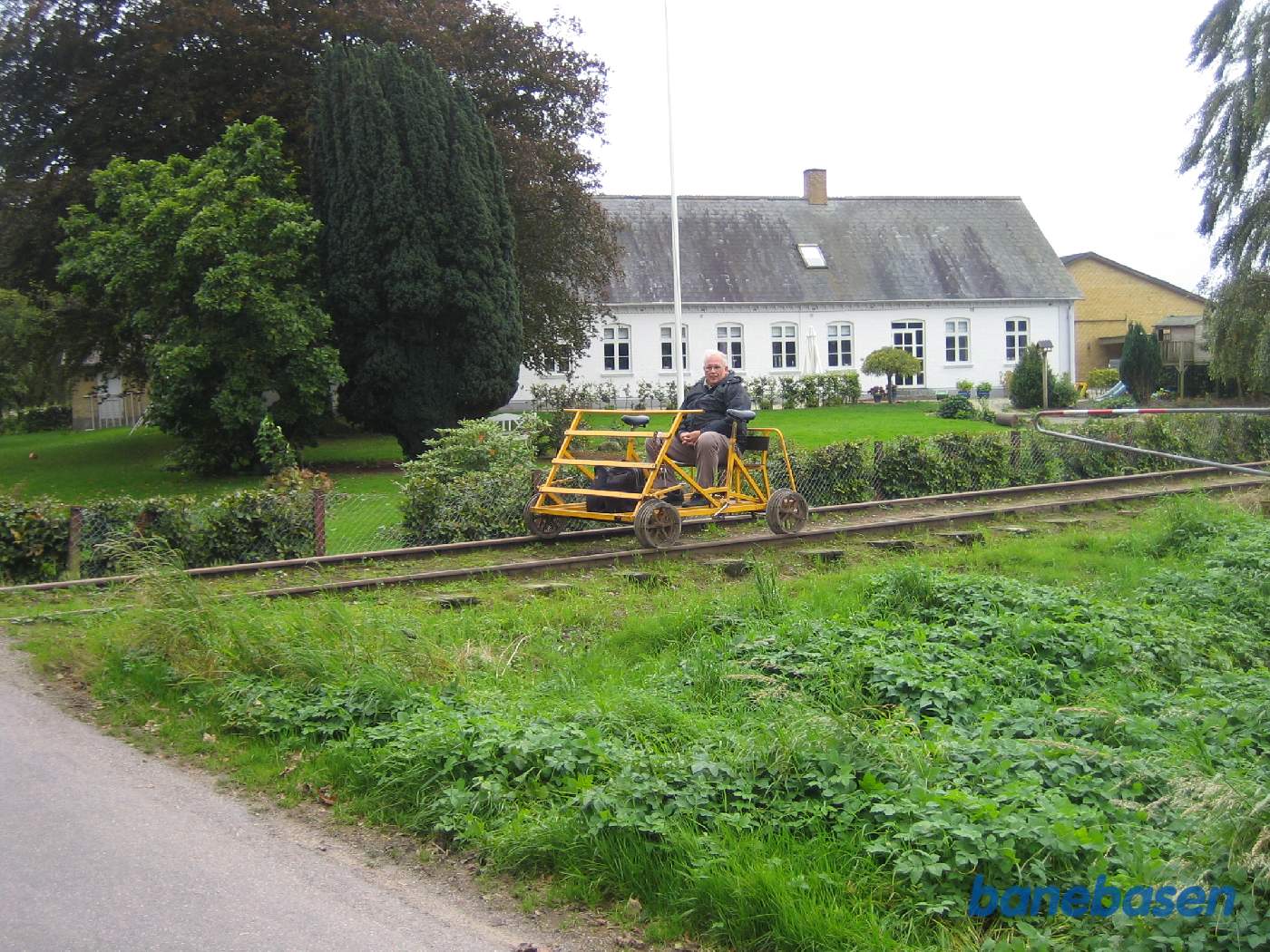 Skinnecyklen holder lige foran overkørslen med Krengerupvej med stuehuset til den store gård i baggrunden
