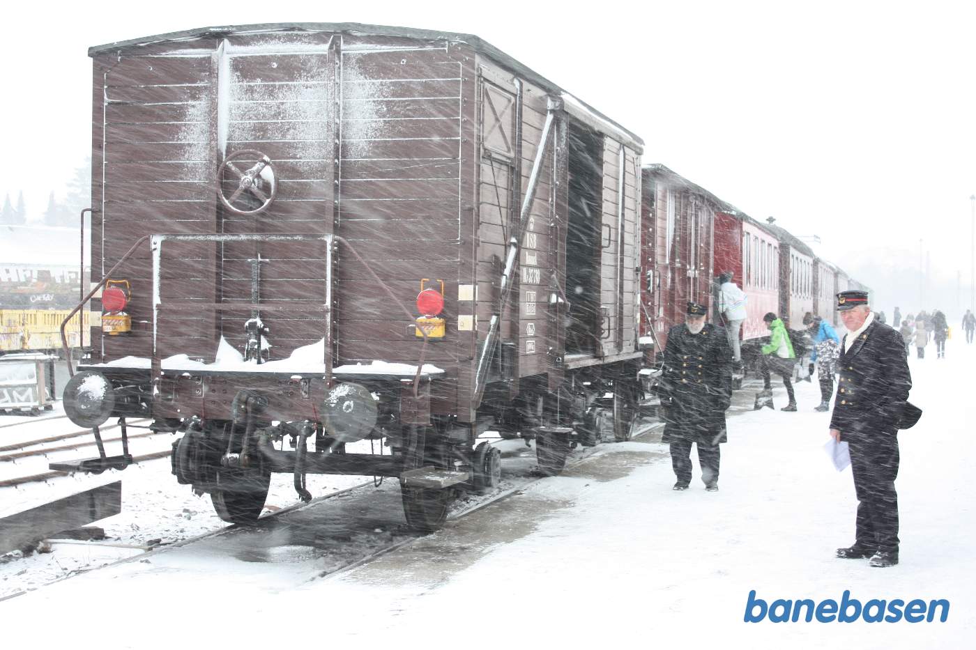 Gæsterne tager straks plads i de opvarmede vogne mens sneen fyger ned over os Gæsterne tager straks plads i de opvarmede vogne mens sneen fyger ned over os