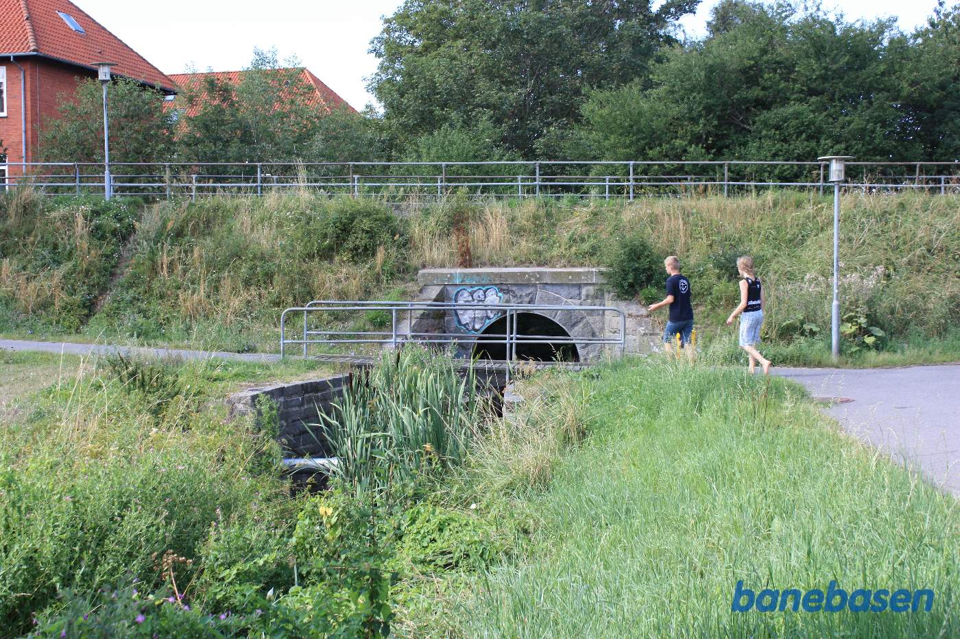 Banen løb oppe på banedæmningen og henover åen, Nexø til venstre og Rønne Nord til højre Banen løb oppe på banedæmningen og henover åen, Nexø til venstre og Rønne Nord til højre
