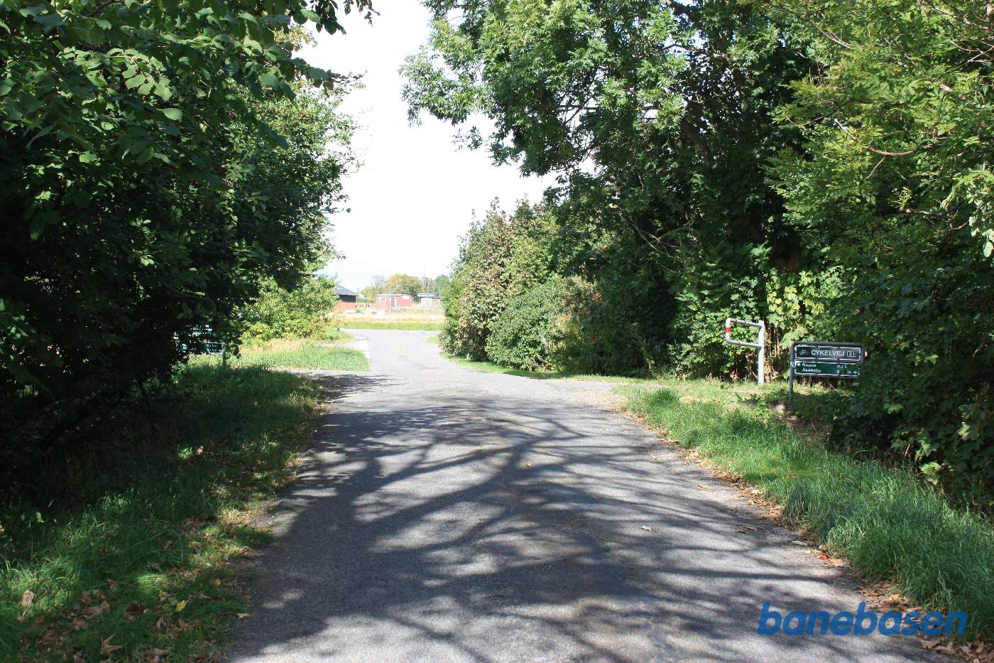 Vi står på en anden overkørsel ved Fejleregårdsvejen, hvor det tydeligt ses, at vejen går op til banens tracé på begge sider, Rønne til venstre og Aakirkeby til højre