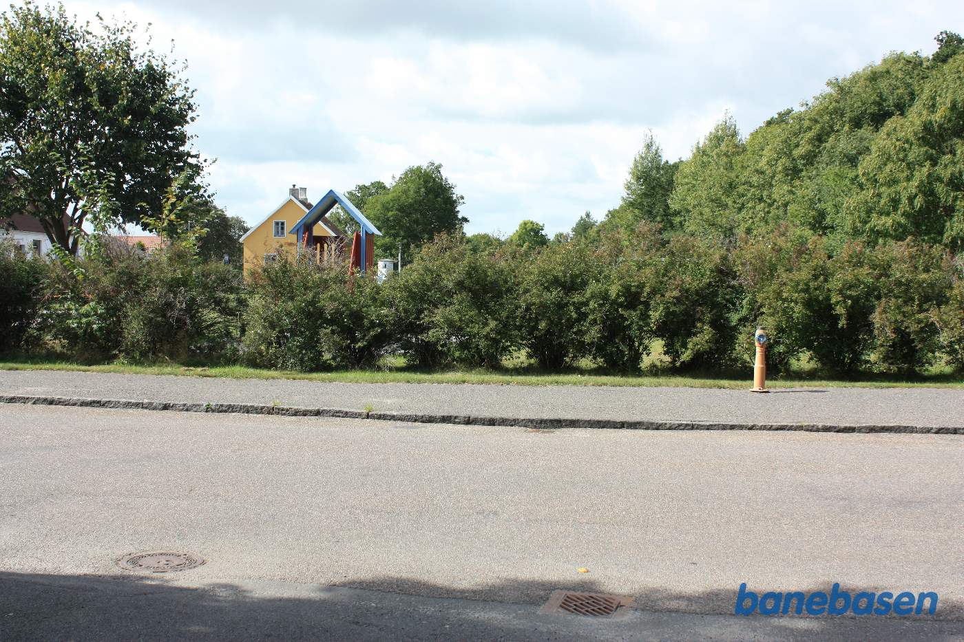 Vi står på Lobbæk Hovedgade. Den gule stationsbygning ses inde bag hækken Vi står på Lobbæk Hovedgade. Den gule stationsbygning ses inde bag hækken