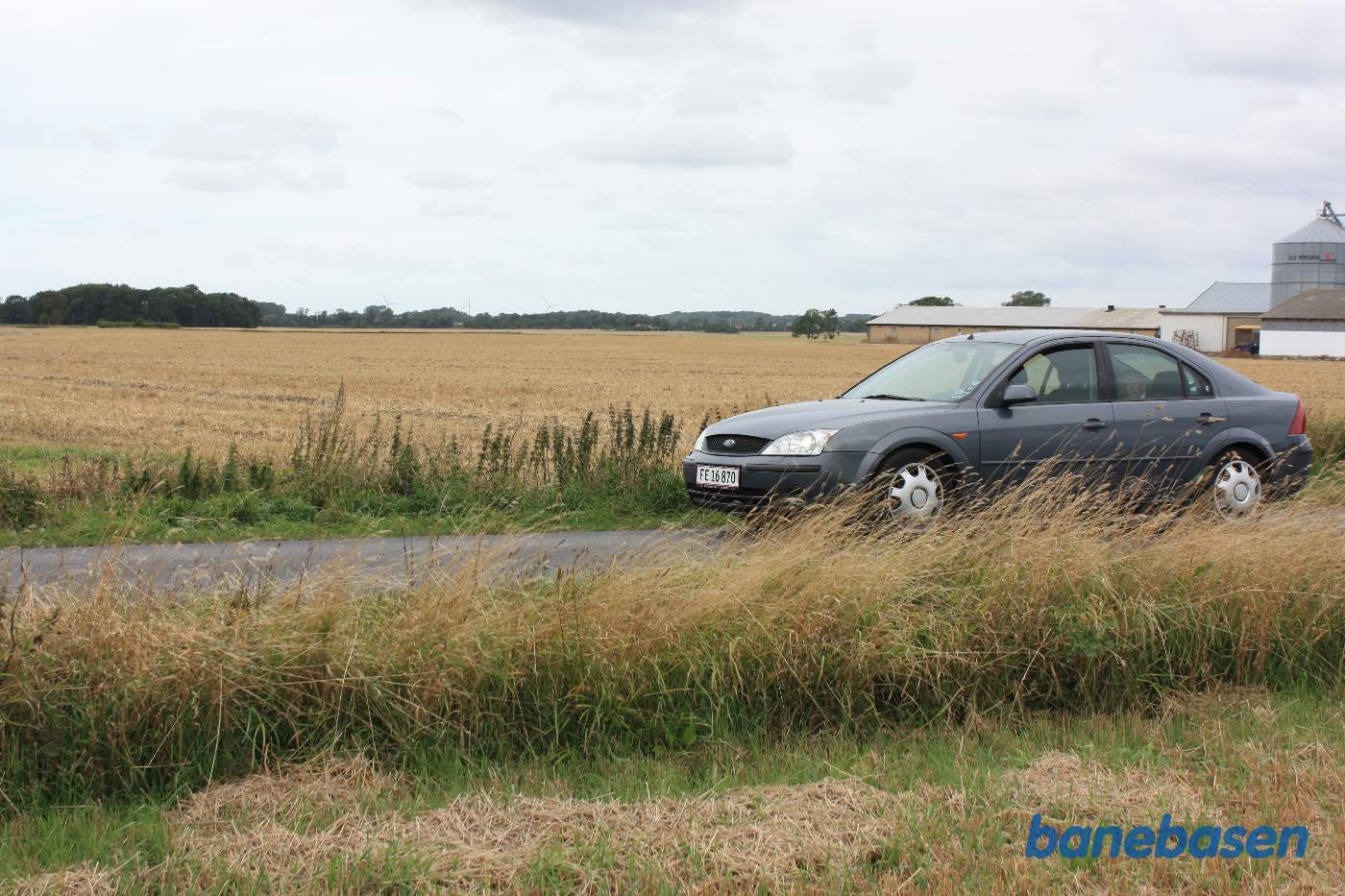 Vi er på Hegnedevejen og bilen markerer, hvor banen krydsede vejen. Vi ser mod Rønne Vi er på Hegnedevejen og bilen markerer, hvor banen krydsede vejen. Vi ser mod Rønne