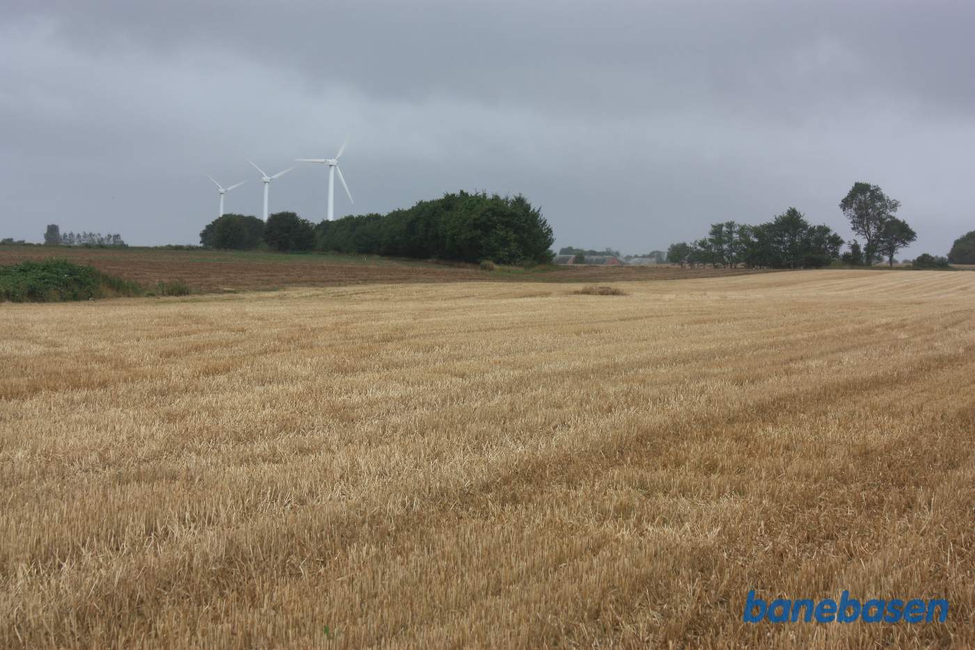Banen løb i en stor bue ud over marken og fortsatte der hvor trærækken midt i billedet begynder. De 3 vindmøller står på banens tracé. Vi kigger mod Rønne