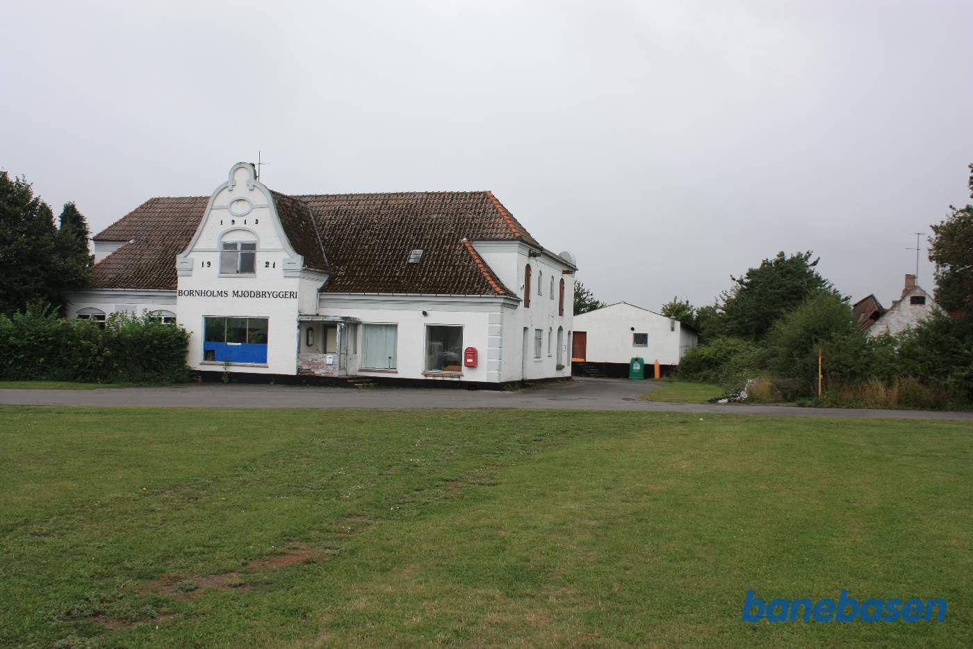 Vi er inde i Bodilsker og kigger mod Rønne, hvor banen kom ind lige til højre for den hvide lagerbygning. Den væltede cykel markerer hvor banen krydsede Vangsbovej