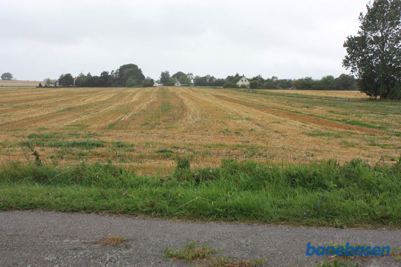 Her krydsede banen Mejerigaden. Banedæmningen mod Rønne er pløjet væk. Stationsbygningen i Bodilsker kan svagt skimtes midt i billedet Her krydsede banen Mejerigaden. Banedæmningen mod Rønne er pløjet væk. Stationsbygningen i Bodilsker kan svagt skimtes midt i billedet