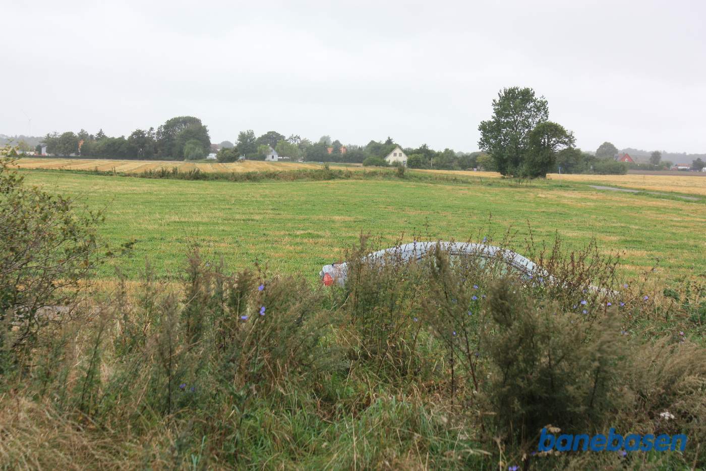 Vi står oppe på den gamle banedæmning og kigger mod Rønne. Stationsbygningen i Bodilsker kan svagt skimtes skråt til venstre Vi står oppe på den gamle banedæmning og kigger mod Rønne. Stationsbygningen i Bodilsker kan svagt skimtes skråt til venstre