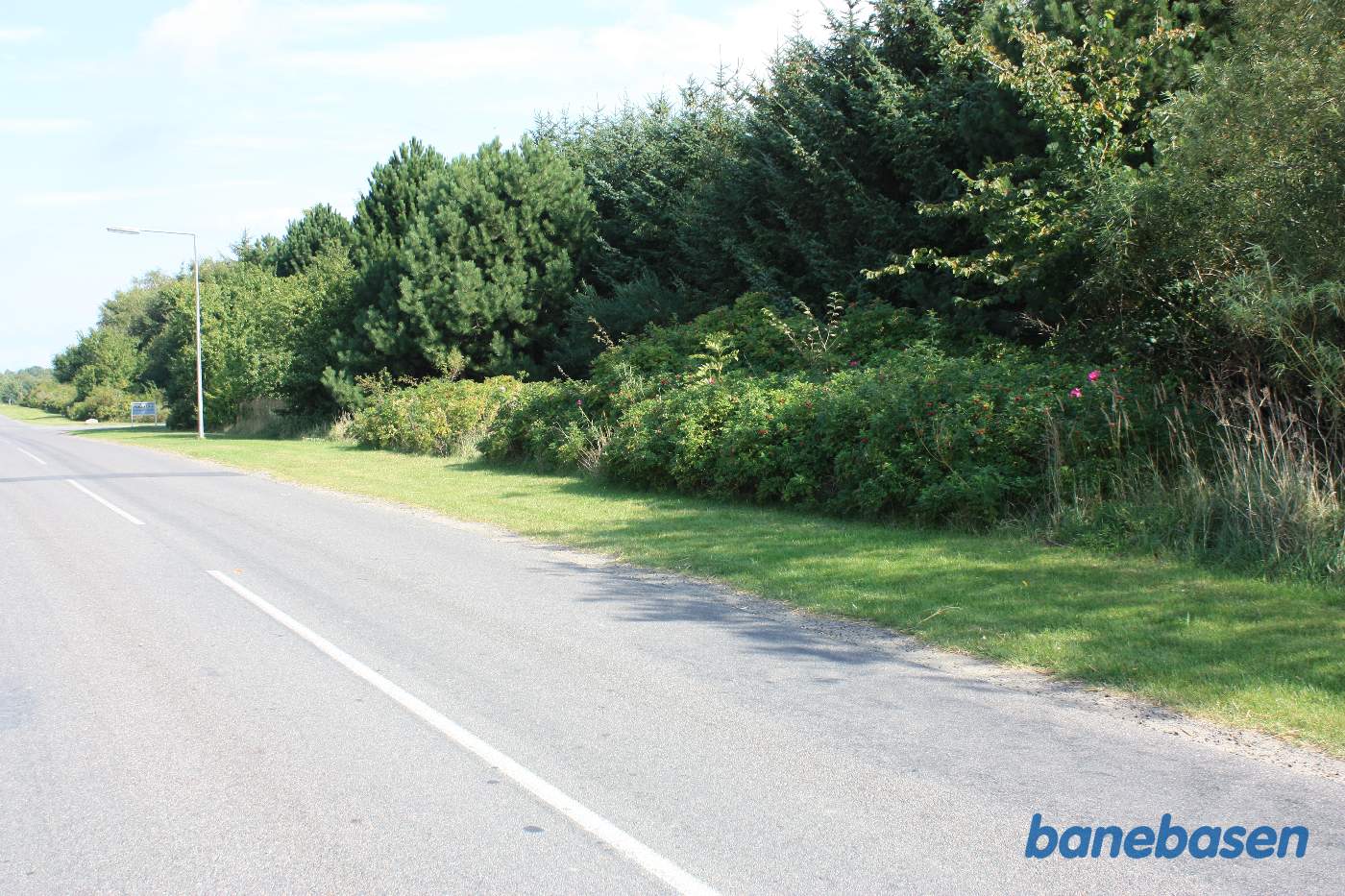 Vi står på Birkevej midt i overkørslen og kigger i retning mod Nexø, hvor banen forsvandt ind mellem træerne Vi står på Birkevej midt i overkørslen og kigger i retning mod Nexø, hvor banen forsvandt ind mellem træerne