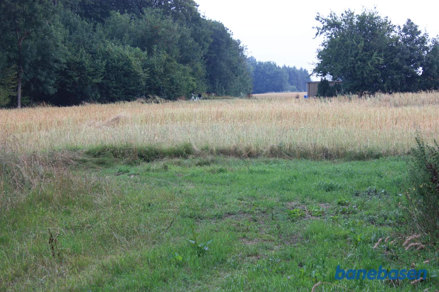 Vi kommer lige ud af skove ved de mange sten og kigger mod Sandvig. Cyklen markerer banens retning Vi kommer lige ud af skove ved de mange sten og kigger mod Sandvig. Cyklen markerer banens retning