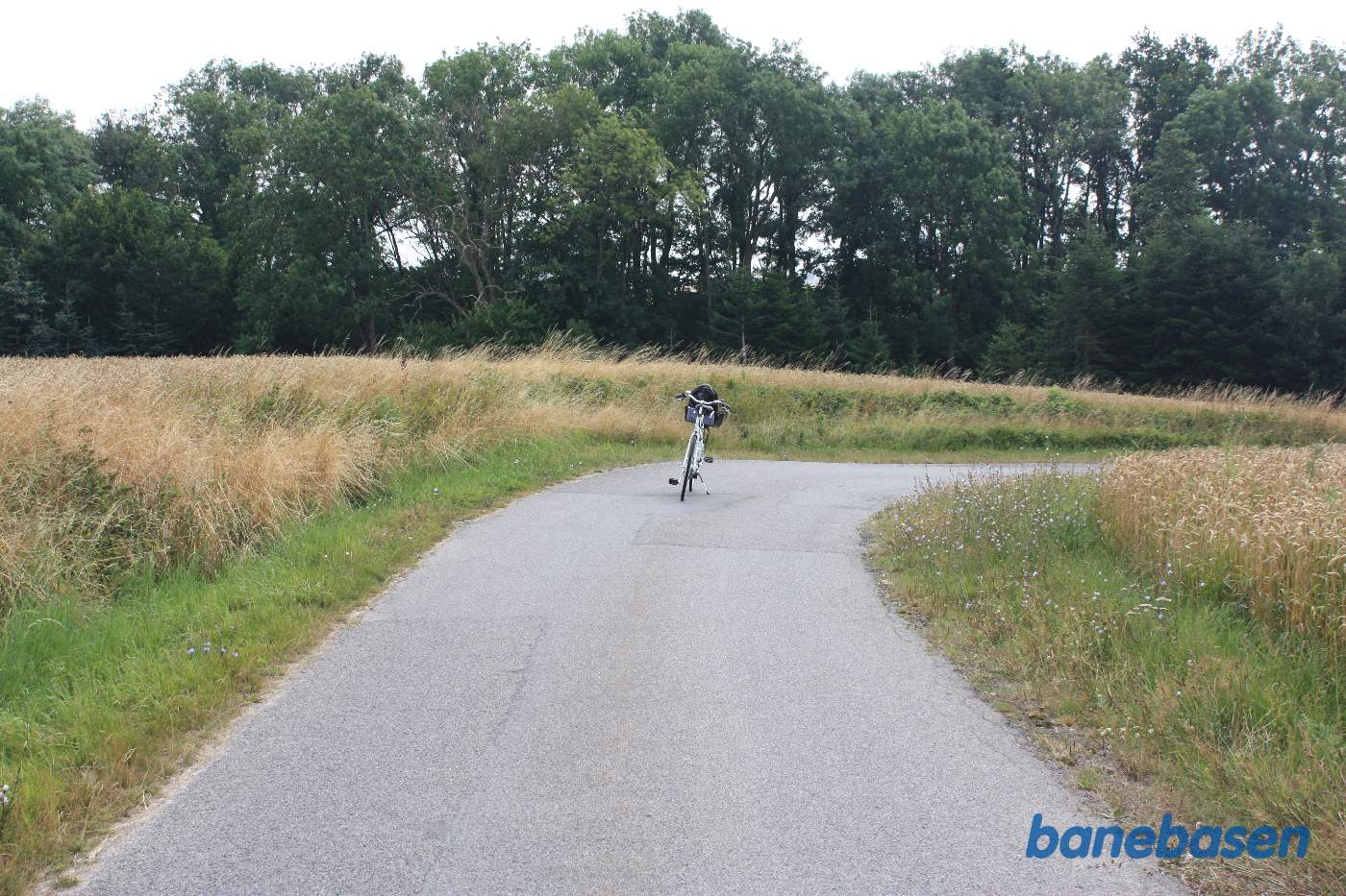 Vi er på Tombyvej og cyklen markerer hvor banen krydsede vejen, Sandvig til venstre og Rønne til højre Vi er på Tombyvej og cyklen markerer hvor banen krydsede vejen, Sandvig til venstre og Rønne til højre