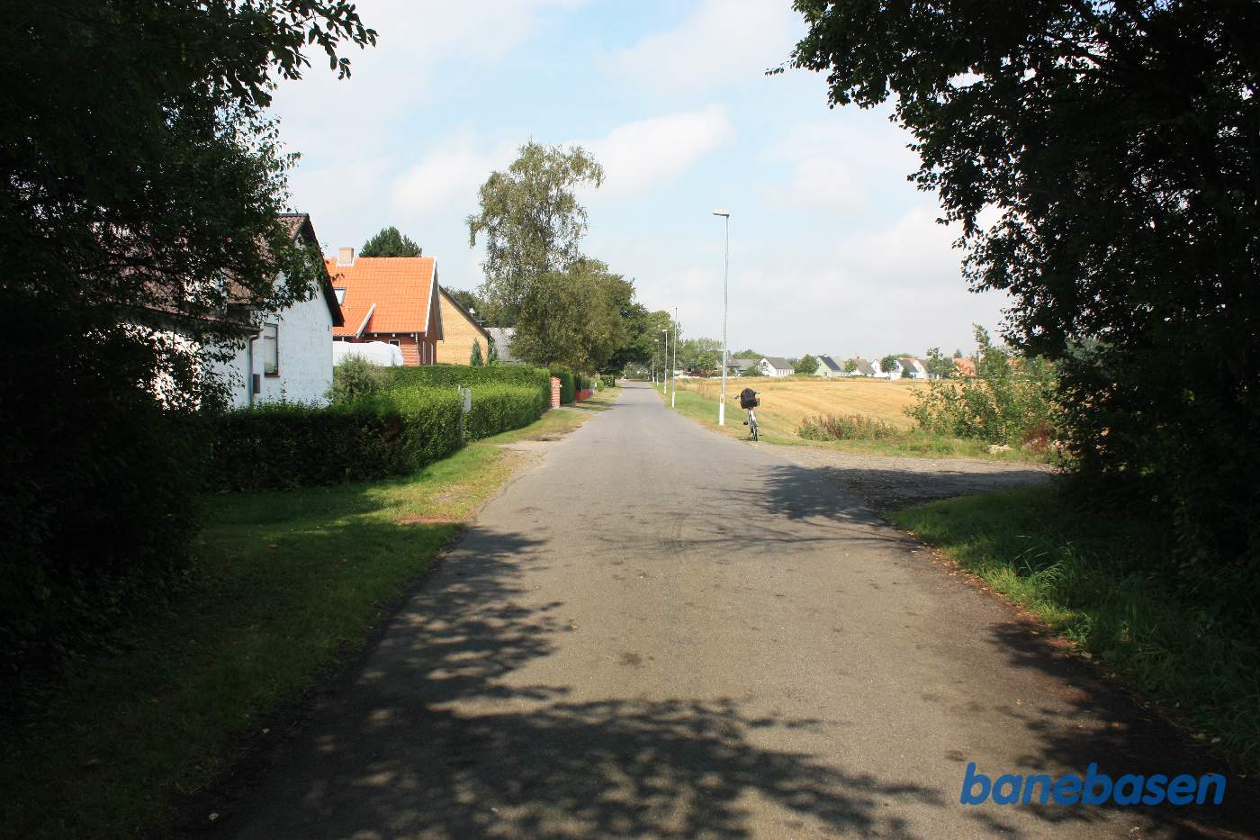 Vi står på Aagaardsvej og banen kom ud fra Rønne i venstre side før hækken, krydsede vejen og fortsatte til højre mod Sandvig Vi står på Aagaardsvej og banen kom ud fra Rønne i venstre side før hækken, krydsede vejen og fortsatte til højre mod Sandvig