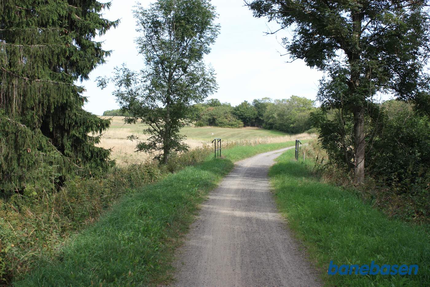 Vi er på banestien i en kurve og kigger mod Sandvig, lille bæk lige foran og golfbane til venstre