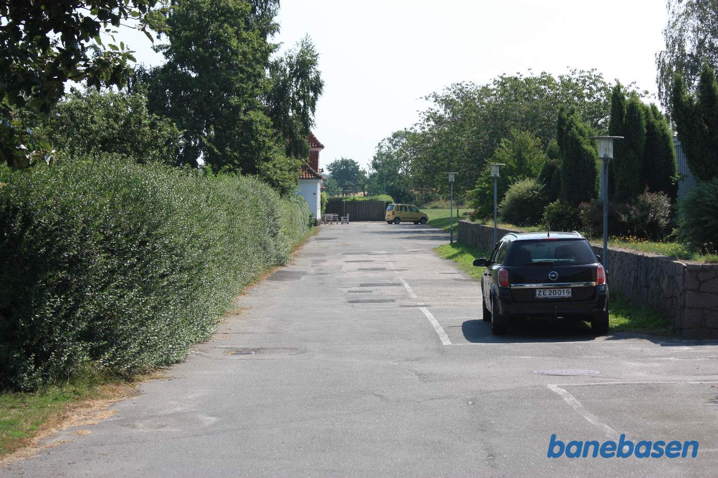 Vi står på vejen op til stationen, stationsbygningen ses bag træerne til venstre Vi står på vejen op til stationen, stationsbygningen ses bag træerne til venstre