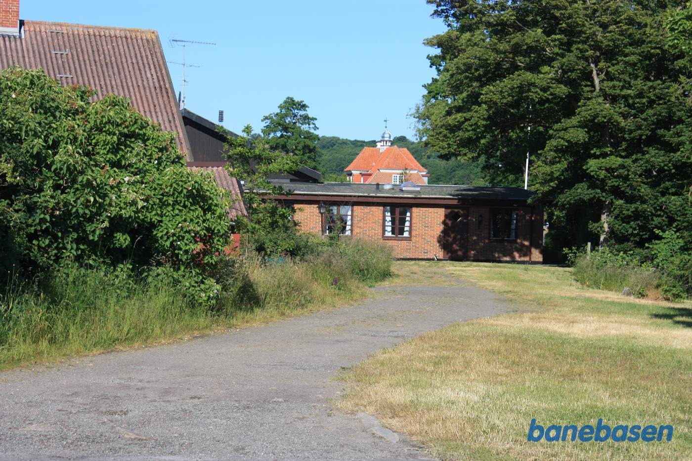 Vi er på vej ind på Sandvig station. Stationsbygningen med det lille tårn ses midt i billedet Vi er på vej ind på Sandvig station. Stationsbygningen med det lille tårn ses midt i billedet