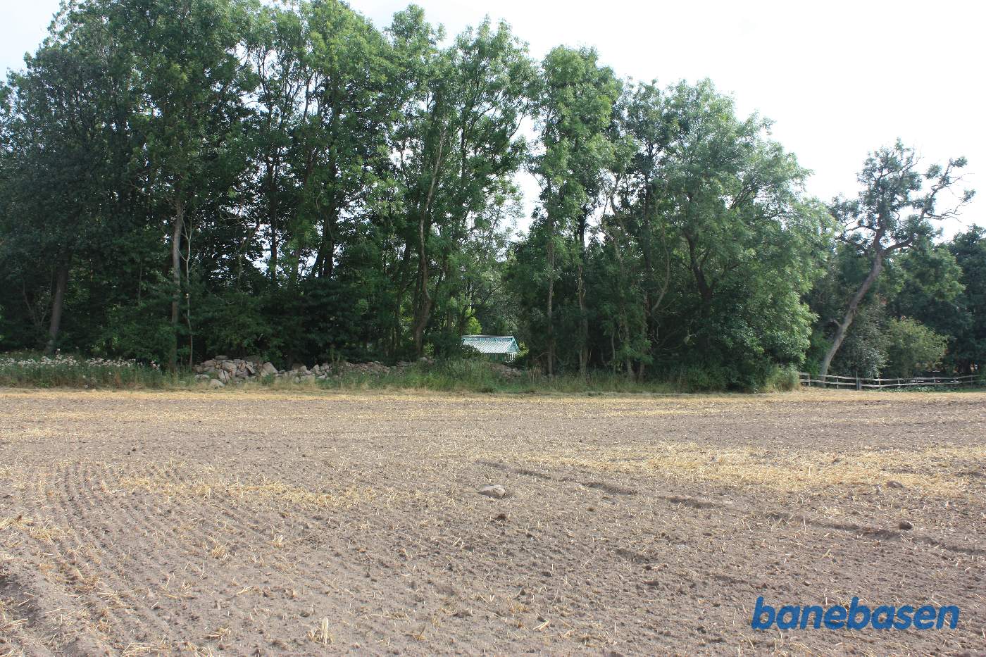 Vi står midt ude på marken og kigger mod Aakirkeby. Banen gik midt i billedet og ind i hullet, hvor drivhuset ligger