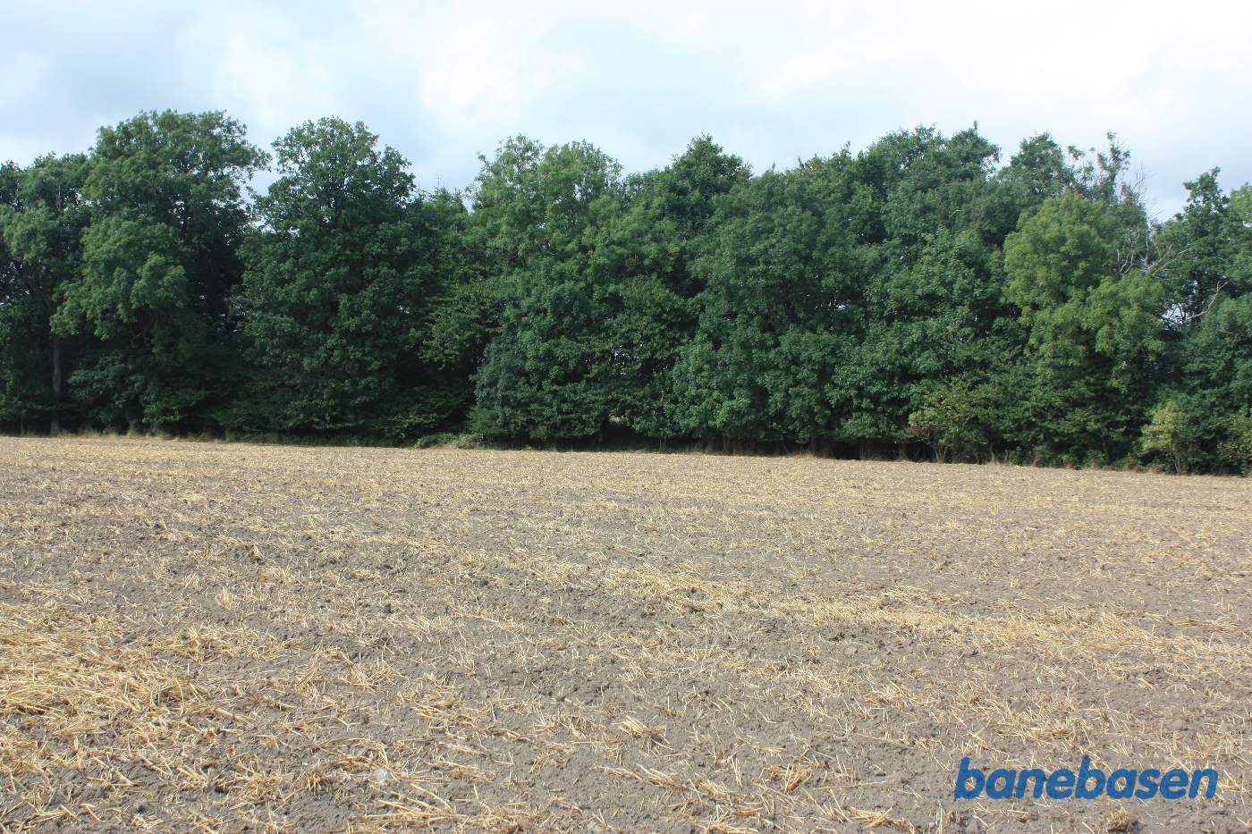 Vi står midt ude på marken og kigger mod Gudhjem. Banen gik midt i billedet og ind i hullet lige for