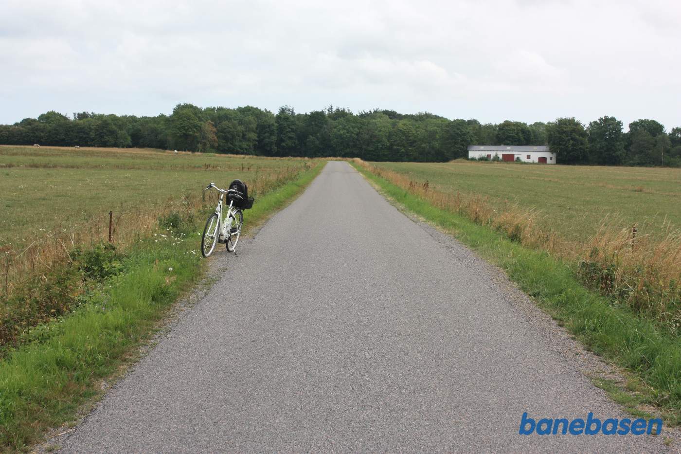 Vi står på Skørrebrovejen. Cyklen markerer hvor banen krydsede over vejen. Gudhjem til venstre og Aakirkeby til højre Vi står på Skørrebrovejen. Cyklen markerer hvor banen krydsede over vejen. Gudhjem til venstre og Aakirkeby til højre