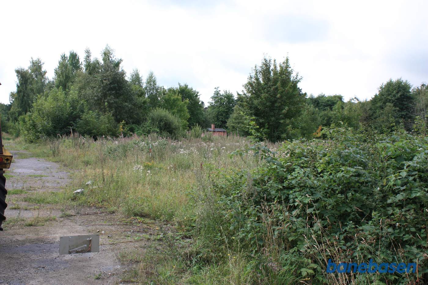 Vi kigger ind på remiseområdet i retning mod Aakirkeby. Man ser lige tag og skorsten på pakhuset midt i billedet Vi kigger ind på remiseområdet i retning mod Aakirkeby. Man ser lige tag og skorsten på pakhuset midt i billedet