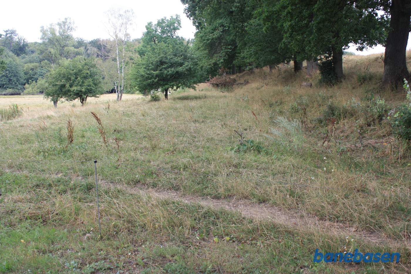 Vi står på Ekkodalsvejen og kigger mod Gudhjem, hvor banen gik gennem skoven og forbi den store gård Rømersdal til venstre for banen Vi står på Ekkodalsvejen og kigger mod Gudhjem, hvor banen gik gennem skoven og forbi den store gård Rømersdal til venstre for banen