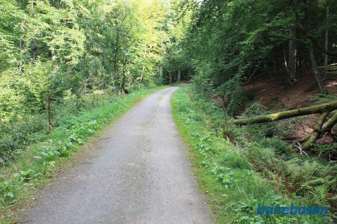 Vi står på banestien og kigger ind i den store bløde kurve til højre i retning mod Gudhjem Vi står på banestien og kigger ind i den store bløde kurve til højre i retning mod Gudhjem