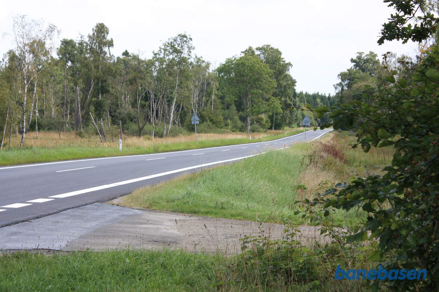 Her krydsede banen Segenvej. På grund af den spidse vinkel mellem vej og bane, fik vejen ved banens anlæg, et par sving, så bane og vej kom vinkelret på hinanden. Vi kigger mod Gudhjem