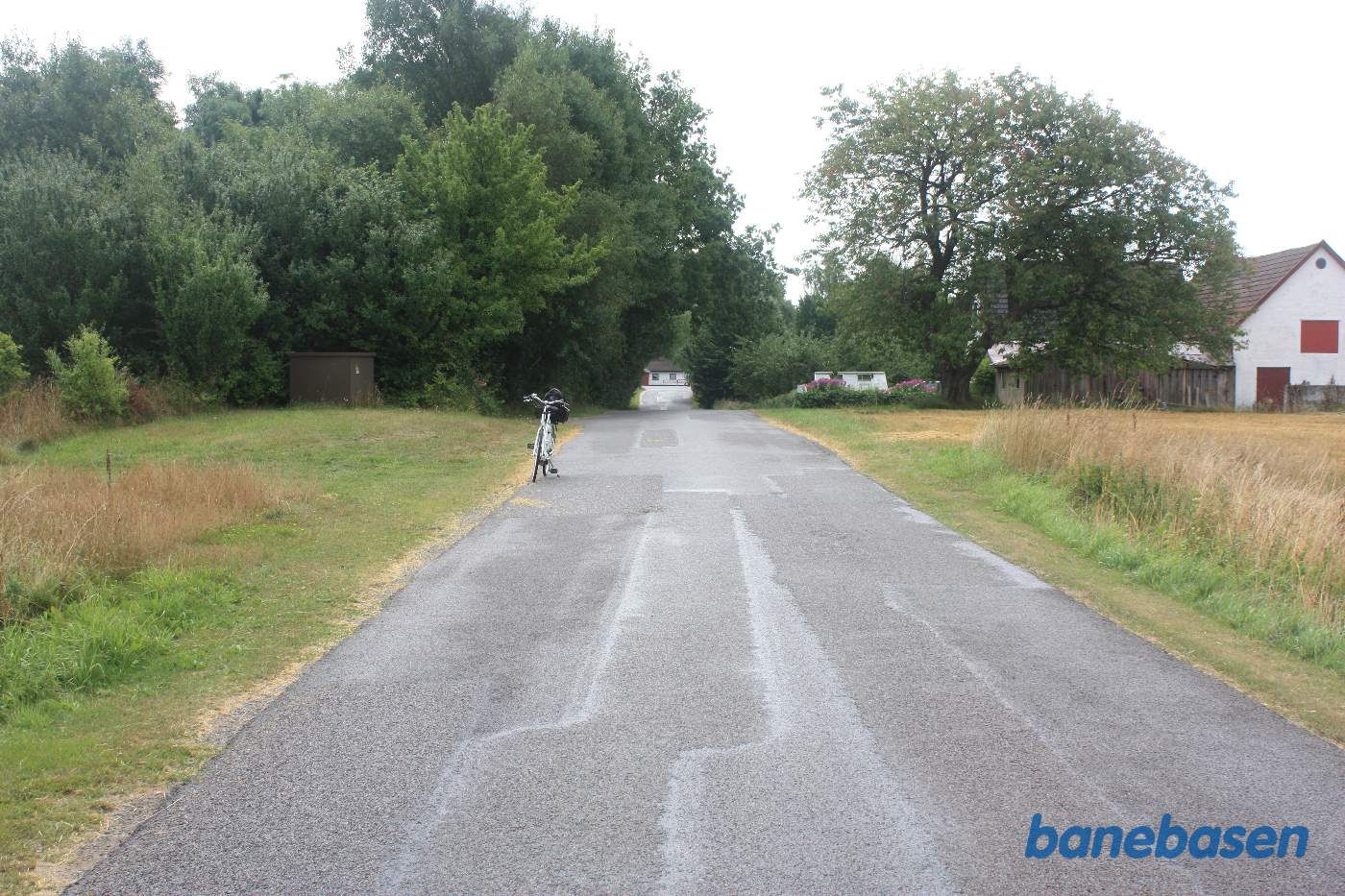 Vi står på Aaløsevej og cyklen markerer hvor banen krydsede vejen, Gudhjem og Aaløse station til venstre, Aakirkeby til højre