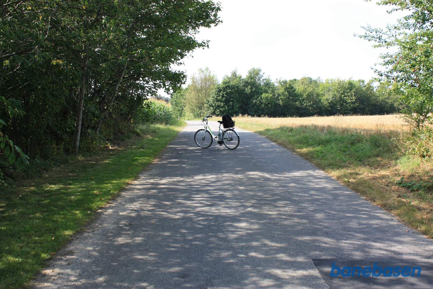 Vi står på Præstegaden hvor cyklen markerer, hvor banen krydsede vejen. Aakirkeby til venstre og Gudhjem til højre