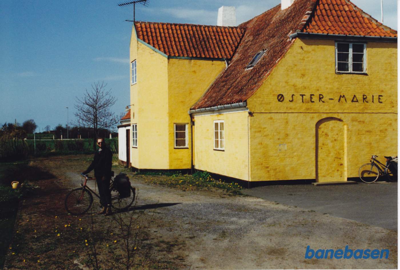 Vi står på Østermarie station på banearealet. Cyklisten står på perronen, men er kommet for sent til toget der er kørt