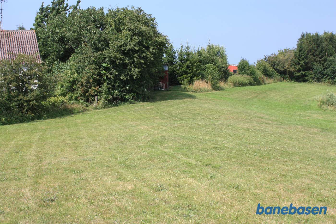 Vi står ved Godthåbsvej, hvor banen krydsede vejen. Man kan stadig fornemme resterne af banedæmningen. Vi kigger mod Gudhjem