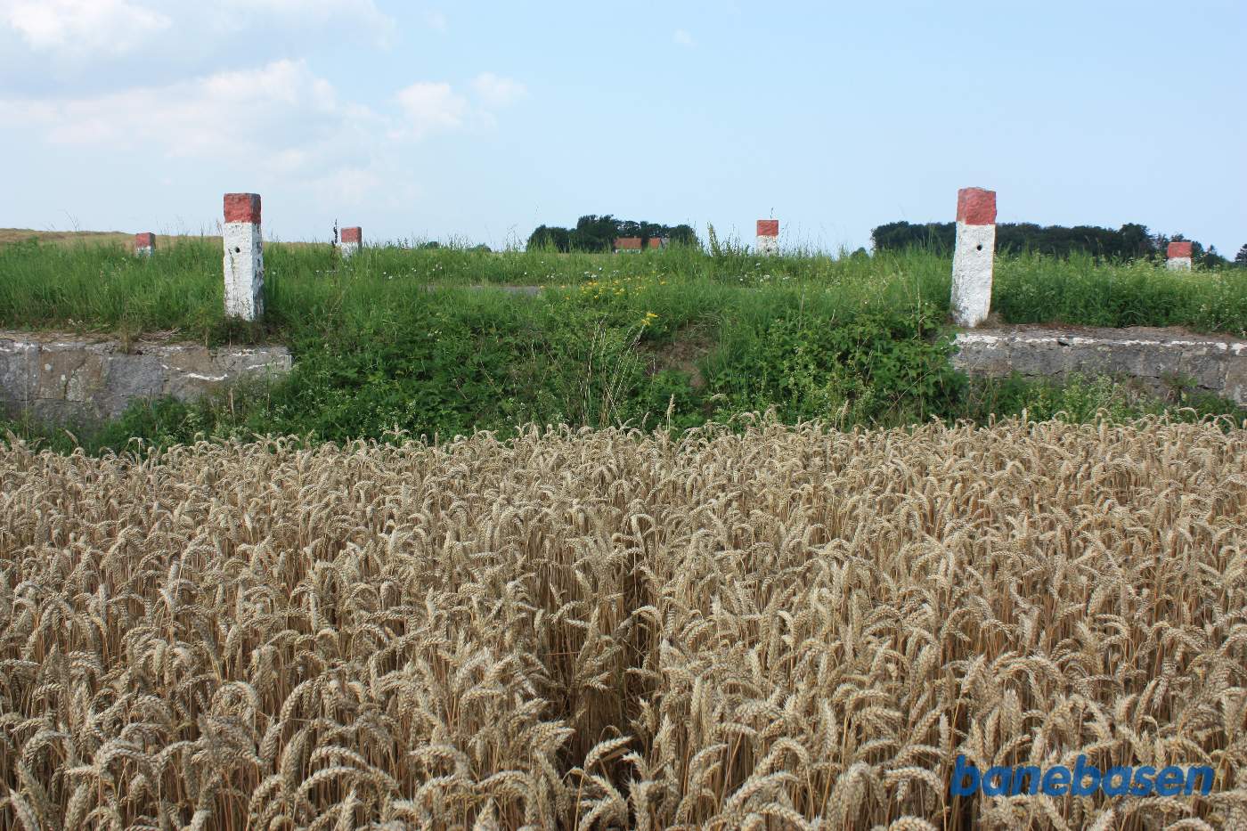 Stedet på Kjeldsebyvej, hvor banedæmningen i sin tid var, ses tydeligt her hvor der ikke er nogen støttemur. Vi ser i retning mod Gudhjem