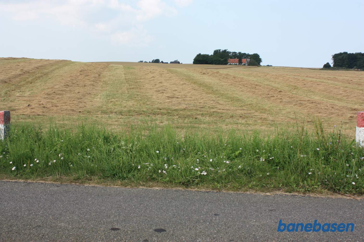 Vi står på Kjeldsebyvej og kigger mod Gudhjem. Banen gik over marken i en skarp venstrekurve på 90 grader