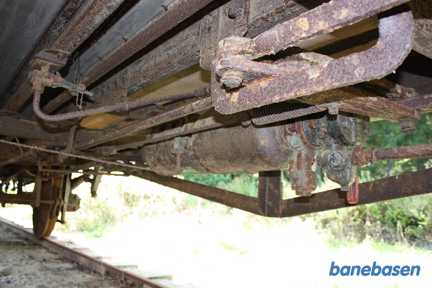 Vi kigger ind under en af vognene i sidesporet, nødbremseventilen til venstre og trykluftbremsesystemet til højre med styreventilen og dens røde afspærringshåndtag