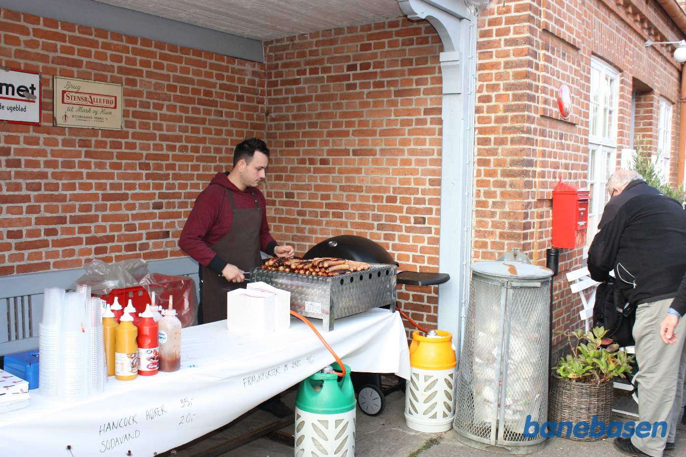 Udenfor på perronen grilles der pølser til café gæsterne